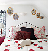 Gilt framed family photographs hang above bed with duvet in rose print motif