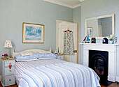 Summer dress hangs on back of door in fresh blue bedroom with original fireplace