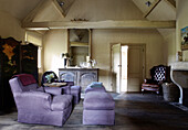 Lilac coloured armchairs with foot rests and folding screen in living room of country home