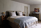 Schlafzimmer eines Landhauses mit bestickten und spitzenbesetzten Bettbezügen in Hellblau und Creme