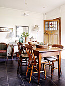 Holztisch und Stühle in einer gefliesten Küche im Landhausstil