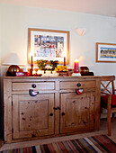 Lit candles on wooden sideboard at Christmas