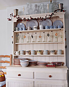 Crockery and glassware on kitchen dresser with Christmas garland