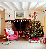 Christmas tree and red armchair at open fireplace with heart shaped decorations
