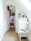 Gift wrapped presents on chair with painted dresser in hallway to bedroom