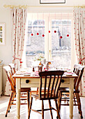 Holzstühle an einem Tisch im Esszimmer mit Weihnachtskugeln im Türrahmen