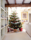 Christmas tree and shelving unit in beamed living room of country home