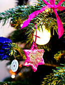Pink star-shaped Christmas decoration on tree