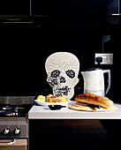 Küchenanrichte mit Totenkopfmuster an der Wand und Brot und Wasserkocher