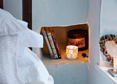 Books and lit candle on recessed bedside shelf