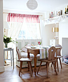 Natural wood dining table and chairs in sunlit room with bench seat