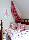 Pink sari fabric above bed with quilt and floral cushions