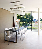 Spacious dining room with glass ceiling lights and view through glass wall to garden exterior