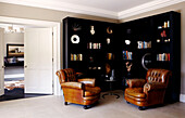 Brown leather armchairs and black bookcase with ornaments