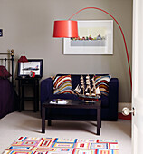 Model ship on side table with purple sofa and red arc lamp