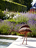 Two bird sculptures stand at garden pond