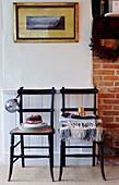 Folded blankets and Christmas cake on wooden chairs at brick fireside