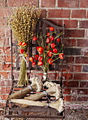 Getrocknete Blumen und Metallstuhl an einer Backsteinmauer in Essex England UK