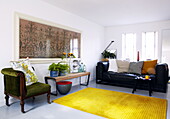 Sessel und Beistelltisch mit schwarzem Ledersofa im Wohnzimmer in Newcastle, England UK