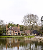 Brick house by village pond in Forest Row Surrey England UK