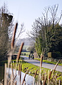 Family walk on country road by stream Forest Row Surrey England UK
