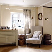 Armchair and sideboard with hat boxes at window of Forest Row farmhouse Surrey England UK
