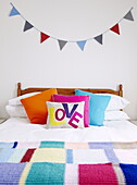 Single word 'LOVE' on colourful pillows double bed with bunting Isle of Wight England UK