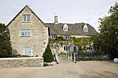 Stone farmhouse with footbridge access and climbing plants in the Cotswolds England UK