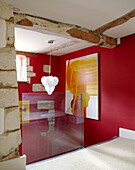 Glass partition on red staircase landing with modern art in renovated Cotswolds mill house England UK