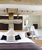 Double bed with en suite bathroom and old mechanism in renovated Cotswolds mill house England UK