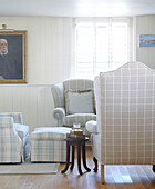 Karierte Sessel und Jalousiefenster im Wohnzimmer eines Hauses in Hampshire, England UK