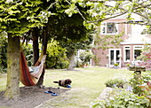 Person in Hängematte liegend mit Hund in der Nähe im Garten des Hauses in Gateshead Tyne and Wear England UK