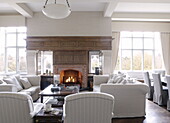 Beleuchtetes Feuer mit weißen Sofas in der Sitzecke eines Landhauses in Tunbridge Wells, Kent, England, UK