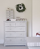 Floral wreath above light grey painted chest of drawers in country house Tunbridge Wells Kent England UK