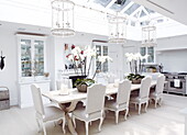 Orchid centrepieces on dining table with lantern light fittings hanging from glass ceiling of London conservatory extension UK