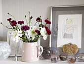 Jug of carnations and glass paperweights with artwork in London home UK
