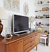 Plasma screen on wooden sideboard with recessed shelving and wall map in Hastings home, East Sussex, UK
