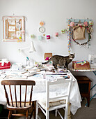 Katze steht am Arbeitstisch mit Schreibtischlampe und zwei verschiedenen Stühlen in modernem Haus, Hastings, East Sussex, UK