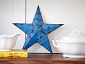 Old blue metal star with ceramic serving dishes and book in Greenwich home, London, UK