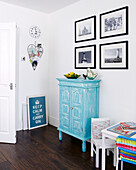 Childs table and chairs with painted cabinet below black and white photographic prints in Greenwich family home, London, UK