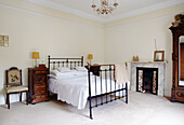 Black painted wrought iron bed with antique wooden bedside cabinets in Warwickshire home, England, UK