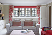 Gestreifte Kissen auf Sofa in Wohnzimmer in Oxfordshire mit geblümten Vorhängen, England, UK