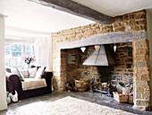 Armchair at stone fireplace in Oxfordshire cottage, England, UK
