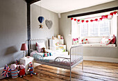 Metal bed on wooden floorboards in child's room of Oxfordshire cottage, England, UK
