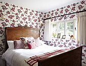 Antique wooden bed in contemporary papered room in Oxfordshire home, England, UK