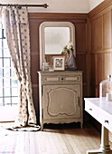 Grey painted side unit and floral curtain in panelled living room of Woodstock home, Oxfordshire, England, UK