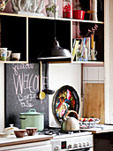 Pfanne und Wasserkocher auf dem Kochfeld mit Tafel und Regalen in der Küche einer modernen Wohnung, Amsterdam, Niederlande