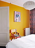Yellow feature wall and wooden chair in bedroom of contemporary family home, Amsterdam, Netherlands