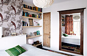 Architectural salvage in contemporary bedroom with bookshelves and patterned wallpaper, Amsterdam, Netherlands