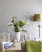 Flower arrangement on dining table in room with metallic leaf patterned wallpaper, Oxfordshire, England, UK
